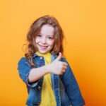 child with her thumbs up