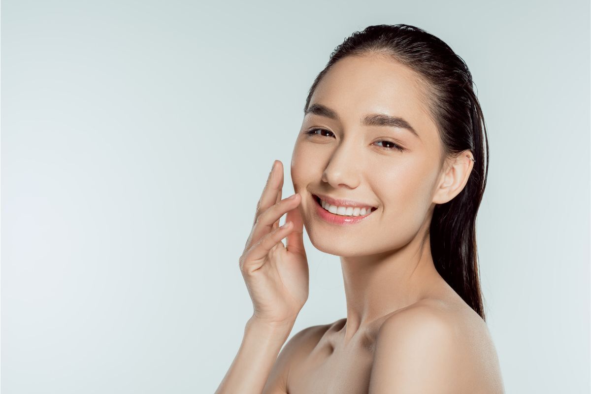 woman smiling while caressing her face